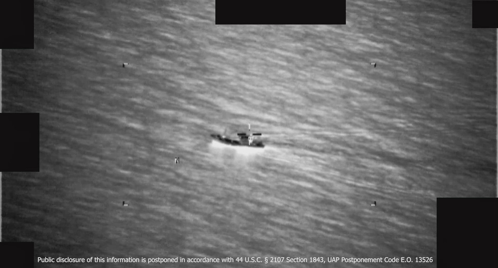 Black-and-white infrared frame of open sea with a small object near the center.